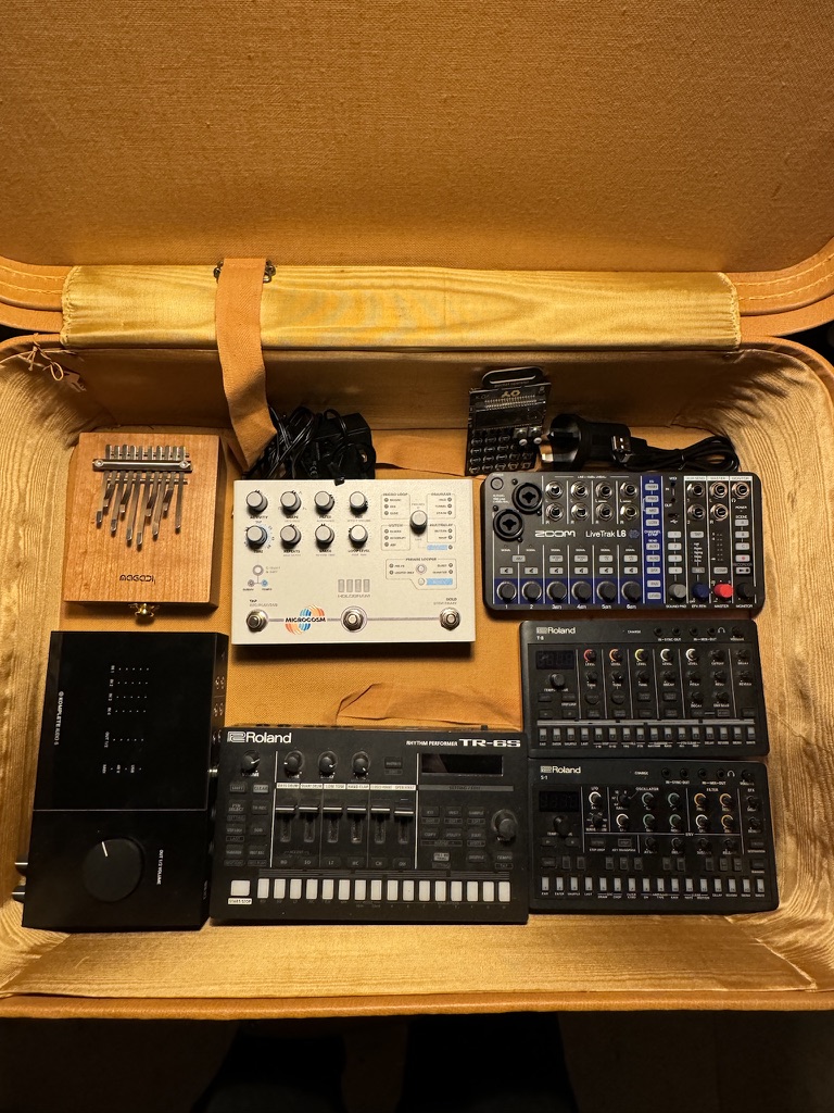 A series of small synths and pedals in a suitcase that is orange/gold coloured